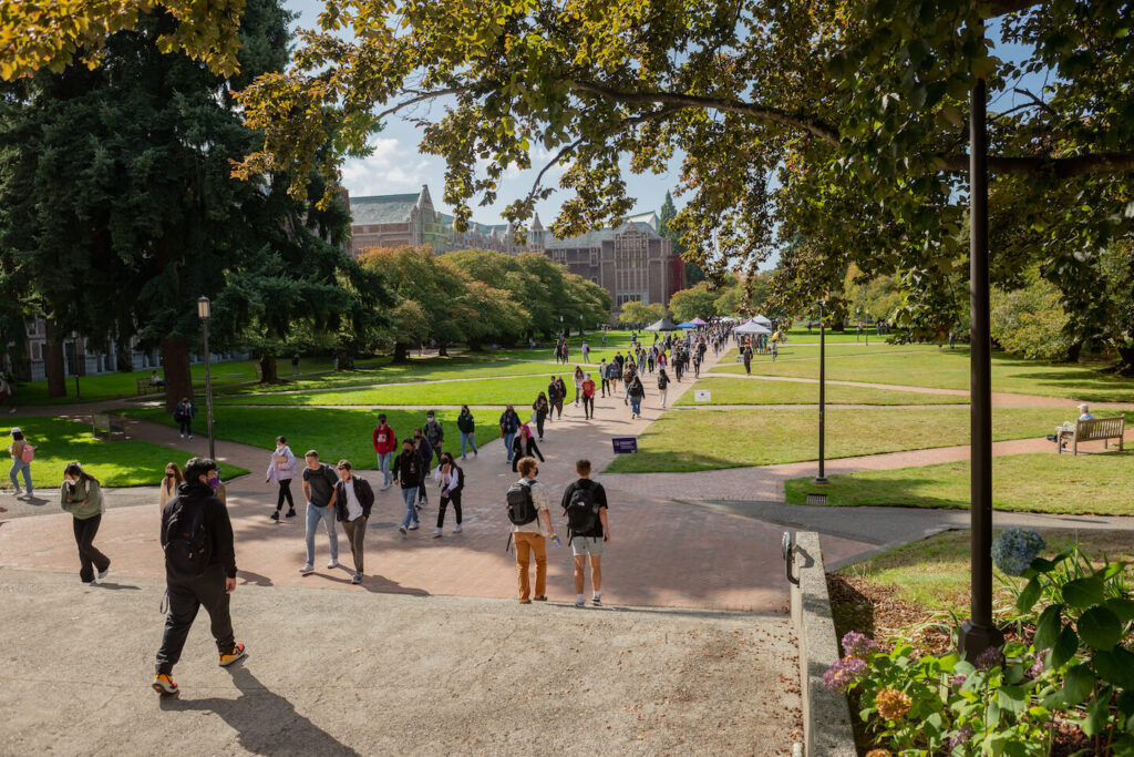 Students walking through the University of Washington campus on a sunny day.