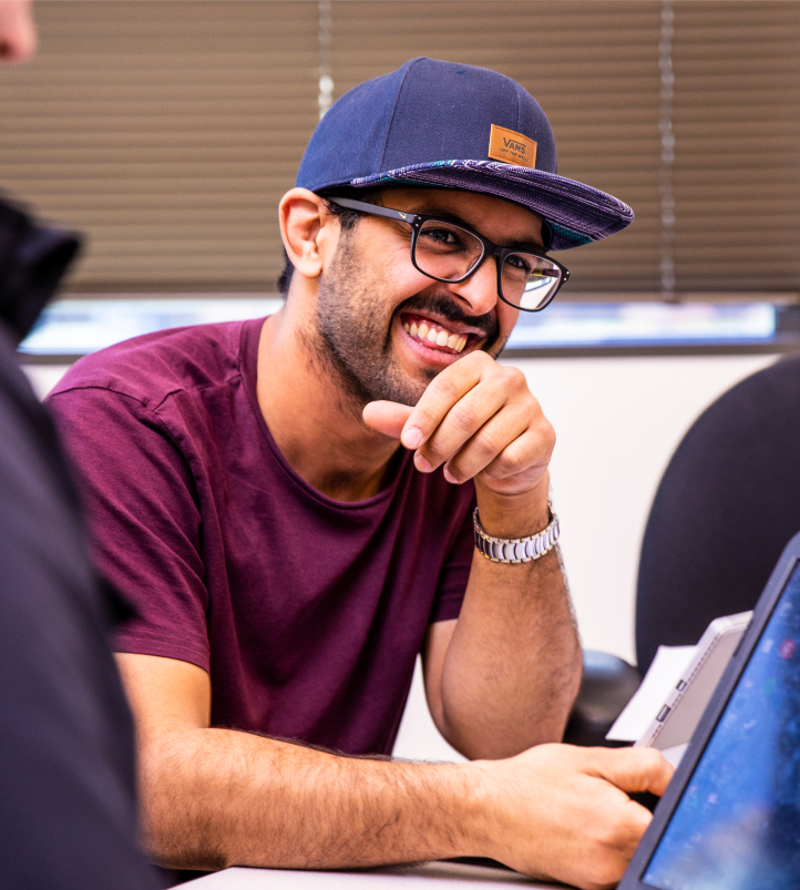 A UW MSIM online student sits at a desk with his laptop.