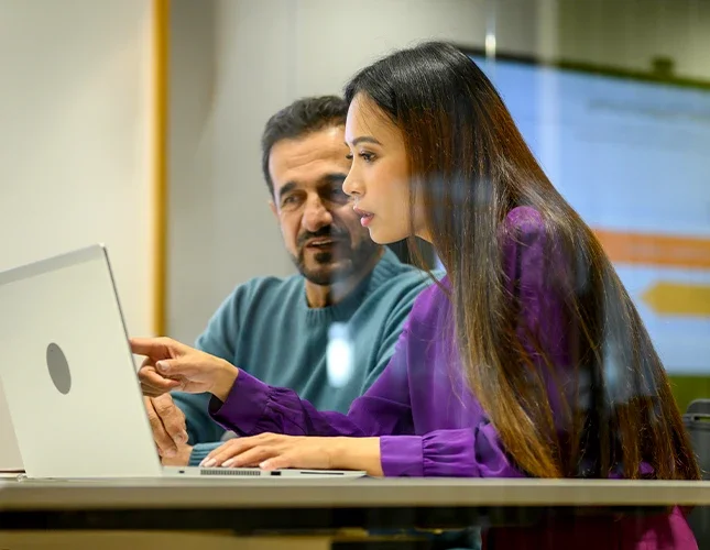Two MSIM students study together in front of a laptop.
